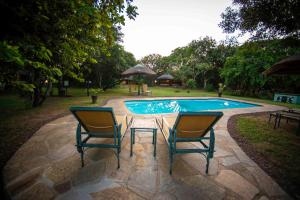 two chairs and a table next to a swimming pool at Gooderson DumaZulu Lodge in Hluhluwe