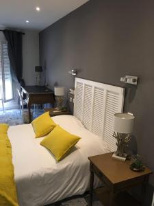 a bedroom with a bed with yellow pillows and a table at Hôtel Le Mistral in Marseille