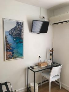 a room with a desk and a tv on a wall at Hôtel Le Mistral in Marseille