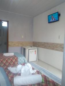 a room with two beds and a tv on the wall at Pousada Vó Nita in Penha