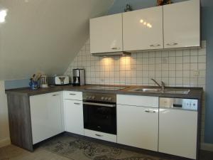 uma cozinha com armários brancos e um lavatório em Norderpiep em Büsum