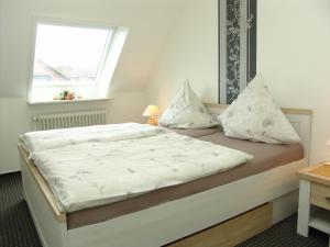 um quarto com uma cama com lençóis brancos e uma janela em Norderpiep em Büsum