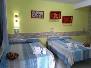 2 Betten in einem Zimmer mit Handtüchern darauf in der Unterkunft Pousada Vó Nita in Penha