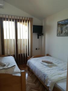 sypialnia z 2 łóżkami i dużym oknem w obiekcie Guest House Jenić w mieście Golubac