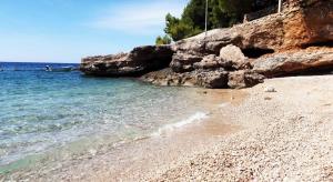 a sandy beach next to the ocean with a boat at Kuća za odmor Lucija in Ivan Dolac
