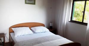 1 dormitorio con 1 cama con sábanas blancas y ventana en Kuća za odmor Lucija, en Ivan Dolac
