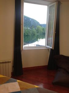 Schlafzimmer mit einem großen Fenster mit Flussblick in der Unterkunft L'Apogée in Thoirette