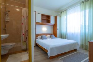 a bedroom with a bed and a toilet and a sink at Apartments & Rooms Sanja in Rab