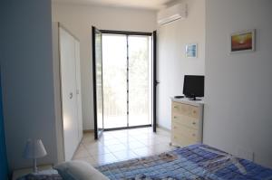 Schlafzimmer mit einem Bett, einem TV und einem Fenster in der Unterkunft Santanna Beach House - Fondachello-apartments com in Mascali