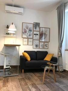 a living room with a black couch and pictures on the wall at Apartments Tessera in Split