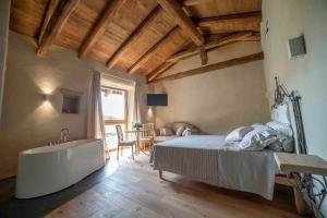 a bedroom with a bed and a tub and a table at Tenuta Armonia in Clavesana