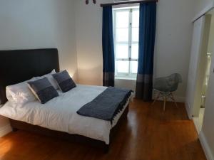 um quarto com uma cama com cortinas azuis e uma janela em 3 Walter Street em Riebeek-Kasteel