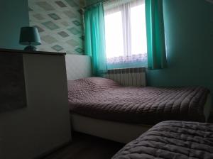 um quarto com 2 camas e uma janela com cortinas verdes em Słoneczna Polana em Solina