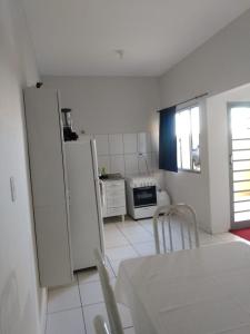 uma cozinha com electrodomésticos brancos e uma mesa e cadeiras em Linda vista em são josé da barra em Elisiário Lemos