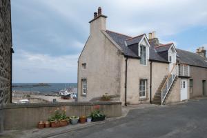 an old house with potted plants on a wall at The Blue Hoose in Gardenstown