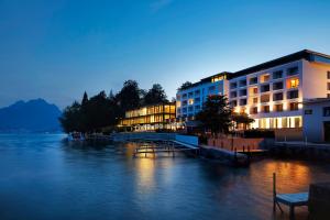 a building next to a body of water at night at Campus Hotel Hertenstein in Weggis