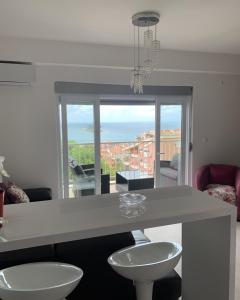 a kitchen with a counter with two white chairs and a table at Urban Apartment in Petrovac na Moru