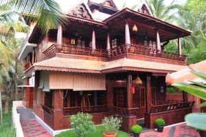 a wooden house with a balcony on the side of it at Omsam Guest Home in Varkala