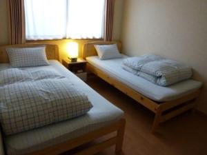 twee bedden in een kleine kamer met een raam bij Guesthouse Mintaro Hut in Yamagata