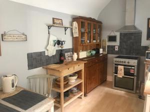 a kitchen with wooden cabinets and a table and a stove at BEAUTIFUL TERRACE COTTAGE HOME, 3 BEDROOM HOUSE near Alton Towers, LEEK Centre, Peak District on doorstep in Leek