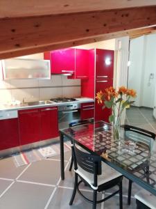 une cuisine avec des placards rouges et une table en verre dans l'établissement Appartamento via Giorgio Canale 72, à Chiavari