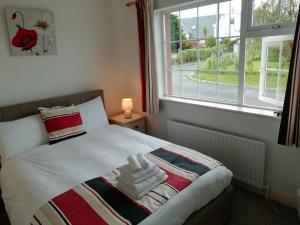a bedroom with a bed with a blanket and a window at Slaney House B&B in Lahinch