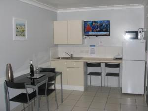 a kitchen with a table and chairs and a refrigerator at Charm City Motel in Bundaberg