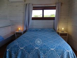 1 cama en una habitación pequeña con 2 velas en las mesas en Casas Sadhana en Punta del Diablo