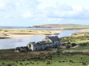 an old house on a hill next to a body of water at Cozy & Remote Hideaway Gintys Cottage in Ross Port +31 photos