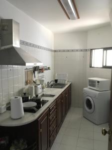 a kitchen with a sink and a washing machine at Chuva De Prata in Caniço