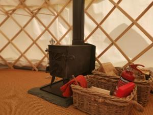 a stove and baskets on the floor in a yurt at Syke Farm Campsite - Yurt's in Buttermere