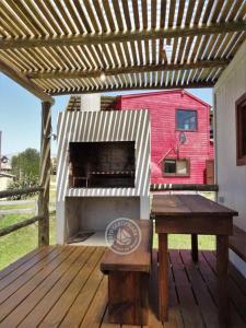a grill on a deck with a table and a bench at Casas Sadhana in Punta Del Diablo