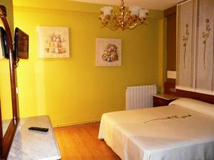 een gele kamer met een bed en een kroonluchter bij Apartamento Turístico Guara Casa Castro in Barbastro