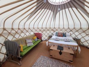 um quarto com uma cama e um sofá numa tenda em Syke Farm Campsite - Yurt's and Shepherds Hut em Buttermere