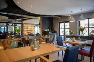 un restaurante con mesas de madera y sillas azules en Campanile Hotel & Restaurant Eindhoven, en Eindhoven