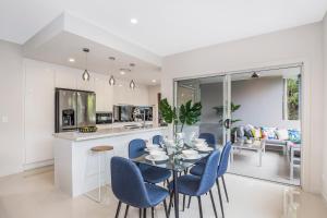 cocina y comedor con mesa y sillas azules en Park Avenue Luxe Townhouse Brand New Sleeps 9 en Brisbane