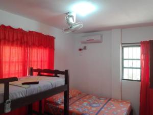 a bedroom with two bunk beds and red curtains at Hostal Casa Yhoanny in Taganga