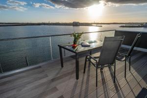 a table and chair on a balcony with a view of the water at Jazz ArT's Penthouse in Olpenitz