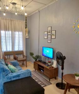 a living room with a blue couch and a tv at The Hidden Gems in Pantai Cenang