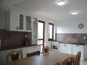 eine Küche mit weißen Schränken und einem Holztisch in der Unterkunft Apartment 2 in Hrabušice