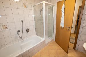 ein Bad mit einer Badewanne, einer Dusche und einem Waschbecken in der Unterkunft Ferienwohnung Ruderich in Hirschaid