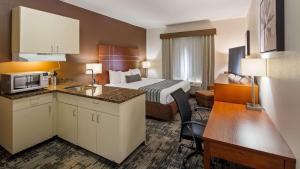 um pequeno quarto de hotel com uma cama e uma cozinha em Best Western Plus Wakeeney Inn & Suites em WaKeeney