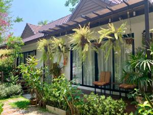 a house with a porch with a chair and plants at Kittawan Home&Gallery in Chiang Mai +55 photos