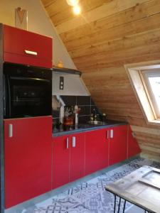 uma cozinha com armários vermelhos e um tecto de madeira em L Annexe em Mittlach