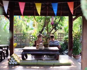 un hombre y una mujer sentados en una mesa en un jardín en Kittawan Home&Gallery en Chiang Mai
