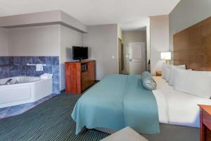 a hotel room with a large bed and a tub at AmericInn by Wyndham Des Moines Airport in Des Moines +40 photos