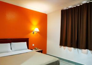 ein Schlafzimmer mit einem Bett und einer orangefarbenen Wand in der Unterkunft Megah Inn in Kota Kinabalu