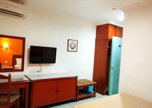 Zimmer mit einem Schreibtisch und einem TV an der Wand in der Unterkunft Megah Inn in Kota Kinabalu