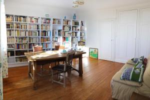 uma sala de estar com uma mesa de madeira e estantes em Maison d'hotes Sainte Genevieve em Sainte-Geneviève