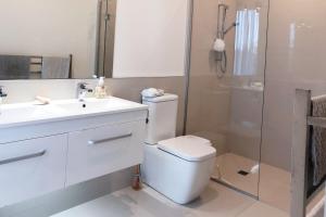 y baño con aseo, lavabo y ducha. en Deluxe Coastal Home & Award-winning Golf en Whangaparaoa